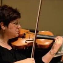A person playing a violin and looking at sheet music.